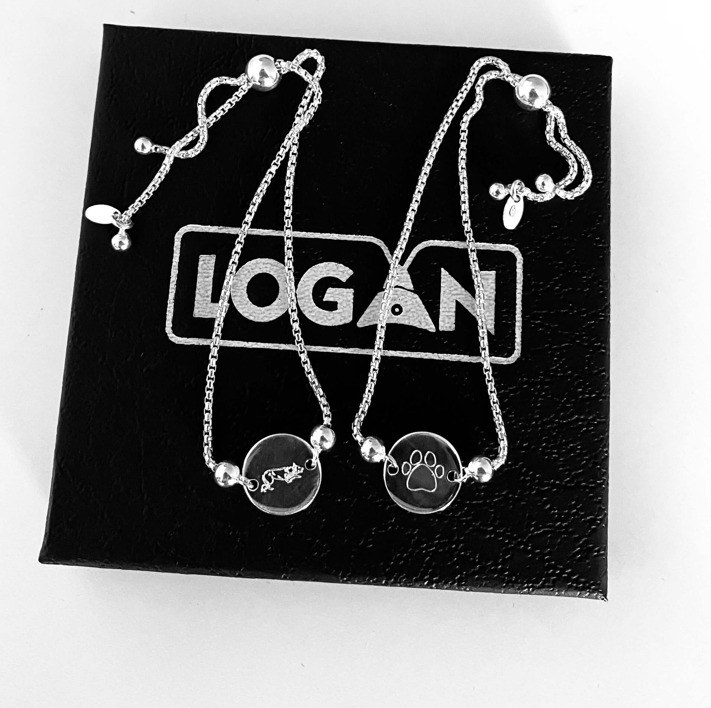 Silver bracelet with paw and Border Collie charms on a black box with 'LOGAN' branding.