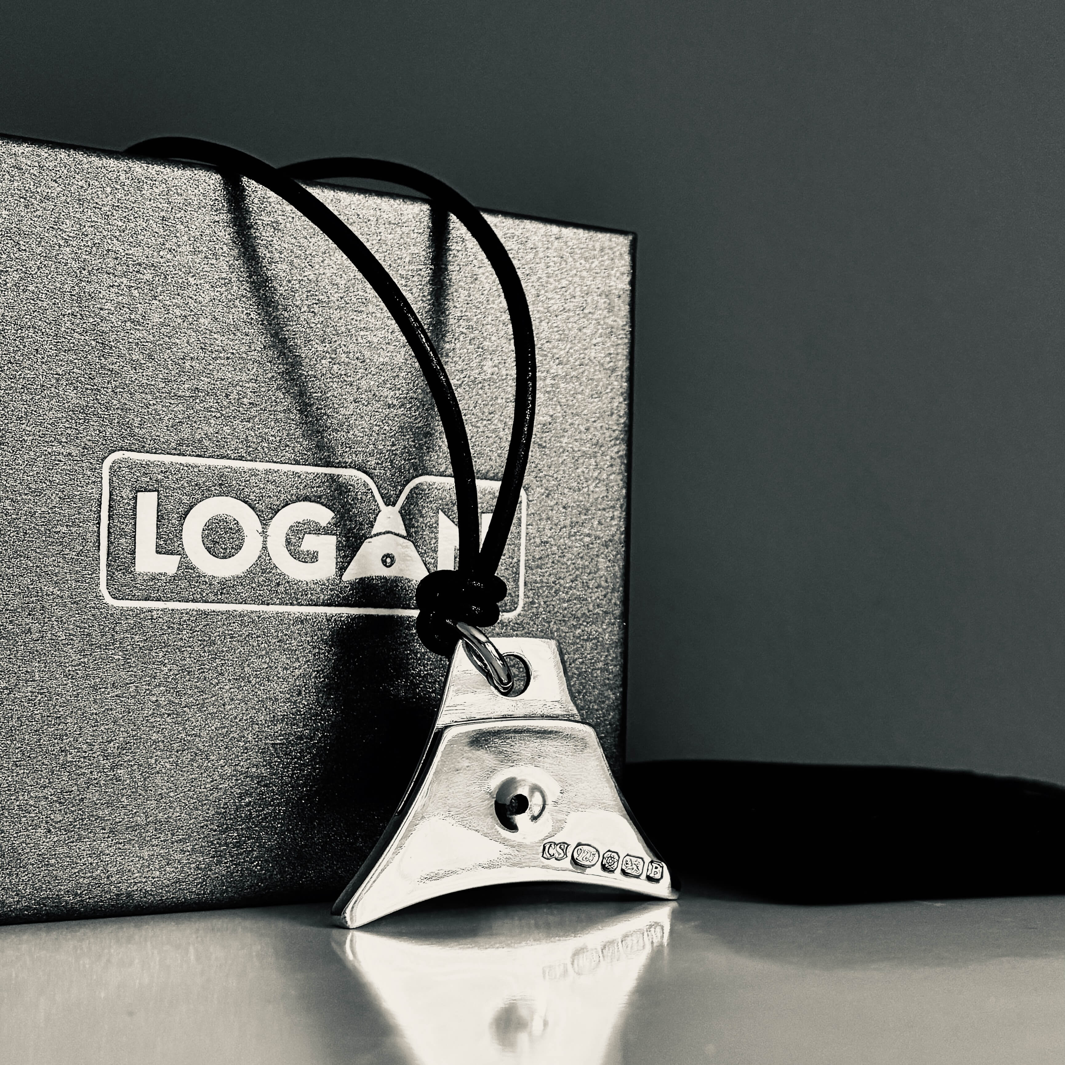 Logan Sterling silver whistle and leather cord lanyard against black box with white Logan Whistles logo