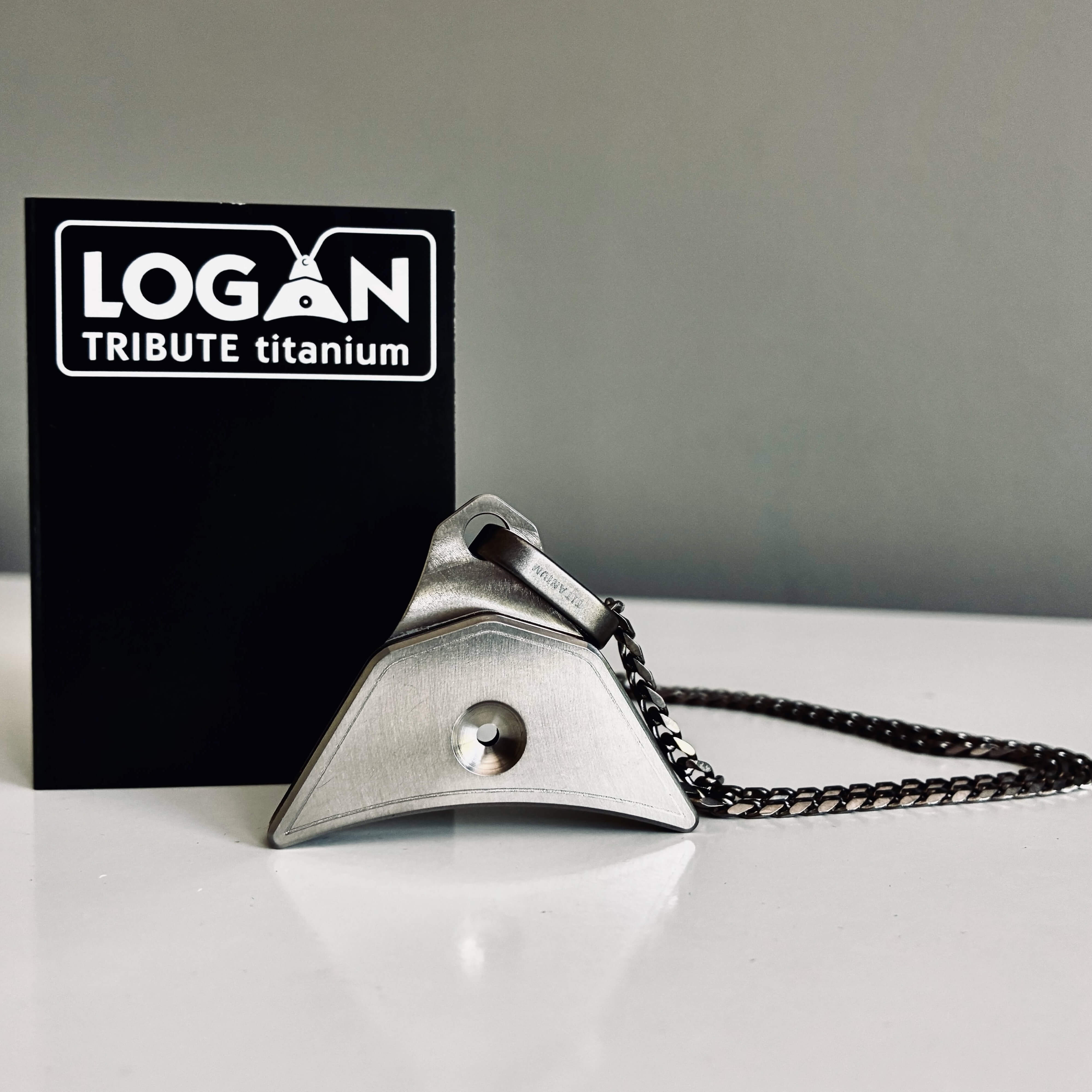 'LOGAN TRIBUTE titanium' whiostle and chain with packaging in the background.