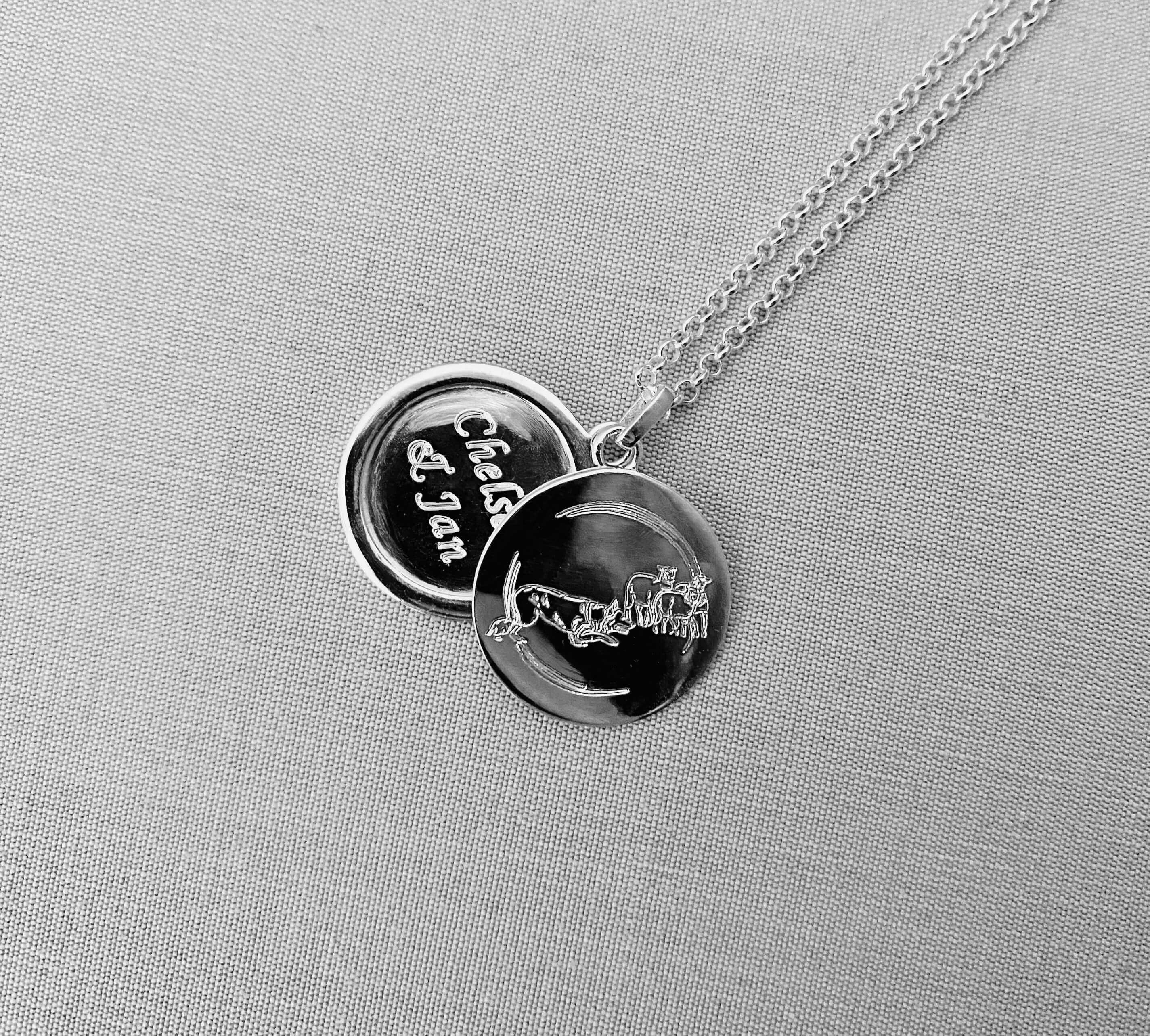 Necklace with two round pendants on a gray fabric background - engraved with sheep and collie