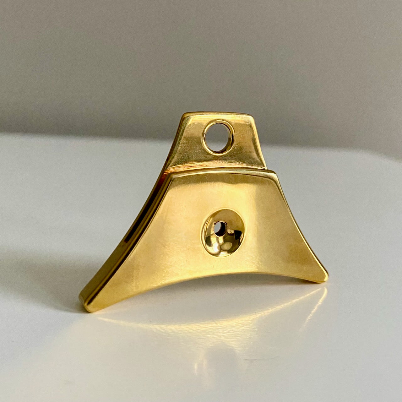 A polished brass Logan Supreme brass sheepdog whistle on a neutral light gray background.